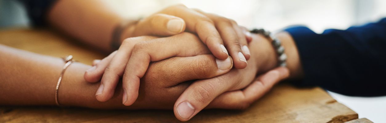 Die Hand eines jungen Mannes in den Händen einer jungen Frau.