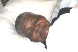 Grace Mbonambi smiles while resting on a white pillow.