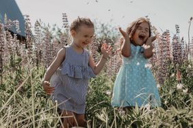 Zwei Mädchen rennen lachend über eine Wiese