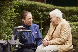 Eine ehrenamtliche Malteserin begleitet eine ältere Dame auf dem Friedhof. 