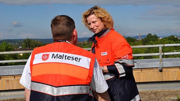 Zwei Malteser in Einsatzkleidung sprechen miteinander nach einem Einsatz.