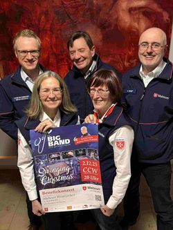 Maltesergruppe hält Plakat für Benefizkonzert