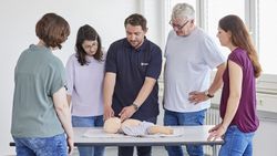 An einer Kinder Dummy Puppe werden erste Hilfe Maßnahmen gezeigt.