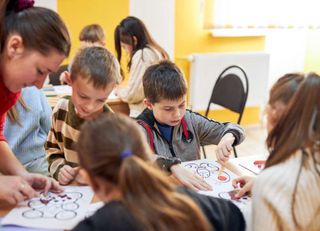 Kinder sitzen an einem Tisch und malen Bilder