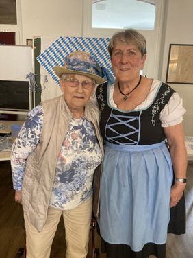 Zwei Frauen stehen nebeneinander und tragen traditionelle bayerische Kleidung in einem Raum.