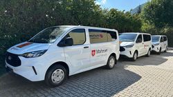 mehrere Kleinbusse mit Malteser Logo parken hintereinander