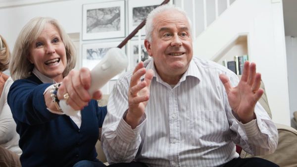 Seniorenpaar spielt an der Wii Konsolenspiele.