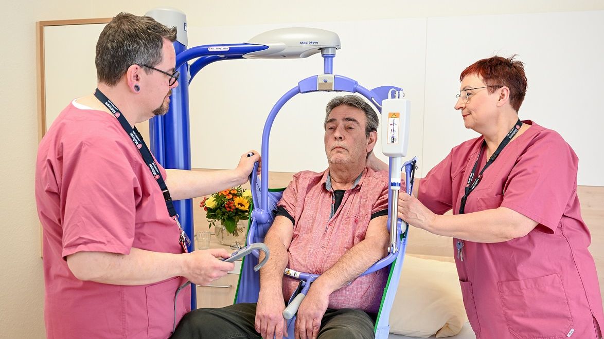 Zwei Pfleger und ein Patient beim Training an einem gerät