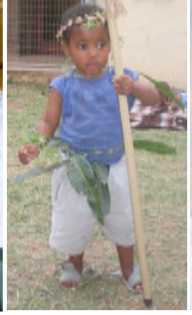 Young child standing in a garden with a walking aid.