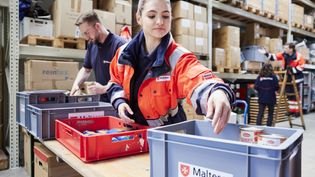 Frau mit Packkiste vor Regal