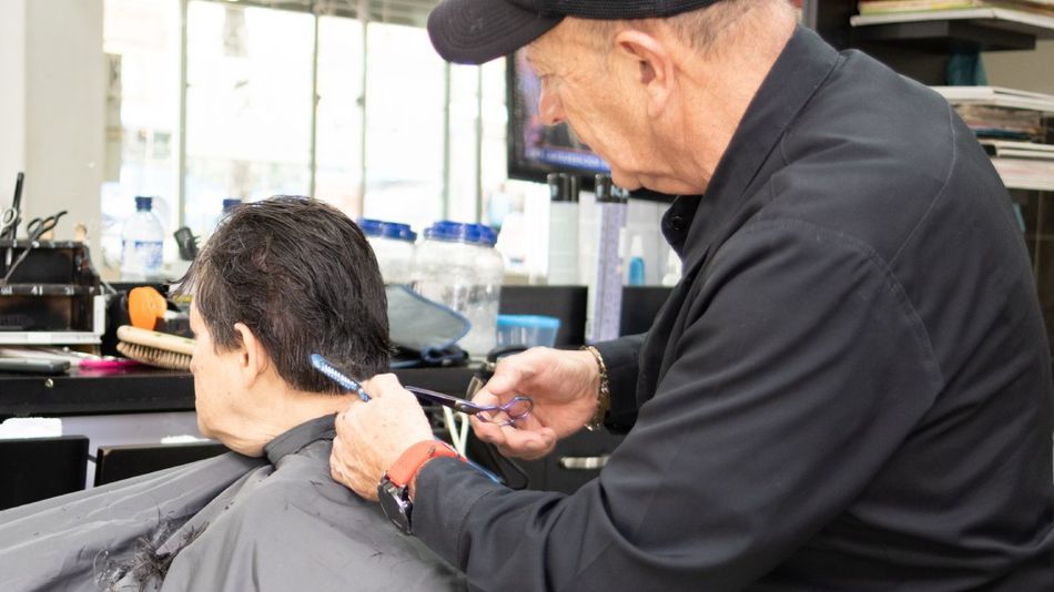 Ein alter Friseur schneidet einer Kundin die Haare