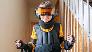 Junge mit Skibrille und Ohrenschützern im Treppenhaus eines Hauses 