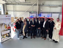 In der Fahrzeughalle der neuen Rettungswache Bad Camberg haben sich zahlreiche Malteser und Vertreter von Stadt und Landkreis eingefunden. Sie stehen vor dem Notarzteinsatzfahrzeug.
