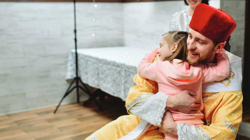 Ein Mann in einer Nikolaus-Verkleidung umarmt ein kleines Mädchen.