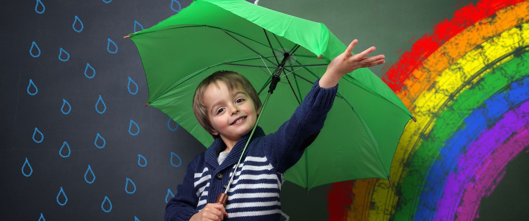 Junge mit einem Regenschirm vor einem gemalten Regen-Sonnenschein-Bild