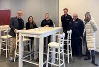 Sechs Personen stehen um einen Stehtisch herum und blicken in die Kamera