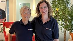 Zwei Frauen stehen Arm in Arm im Café Malta und lächeln in die Kamera.