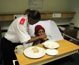 A nurse helps a patient with a meal in bed.
