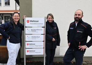 Drei Personen an einer Stele mit Beschreibung des Gebäudes hinter ihnen