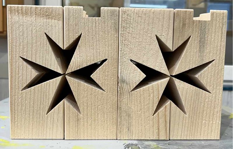 Holz-Werkstücke aus denen das Malteserkreuz herausgesägt wurde.