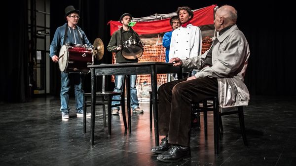 Menschen in Verkleidung und mit Musikinstrumenten auf einer Theaterbühne