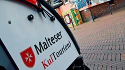 Eine Fahrradrikscha vor einem Hauswandgemälde in Hildesheim