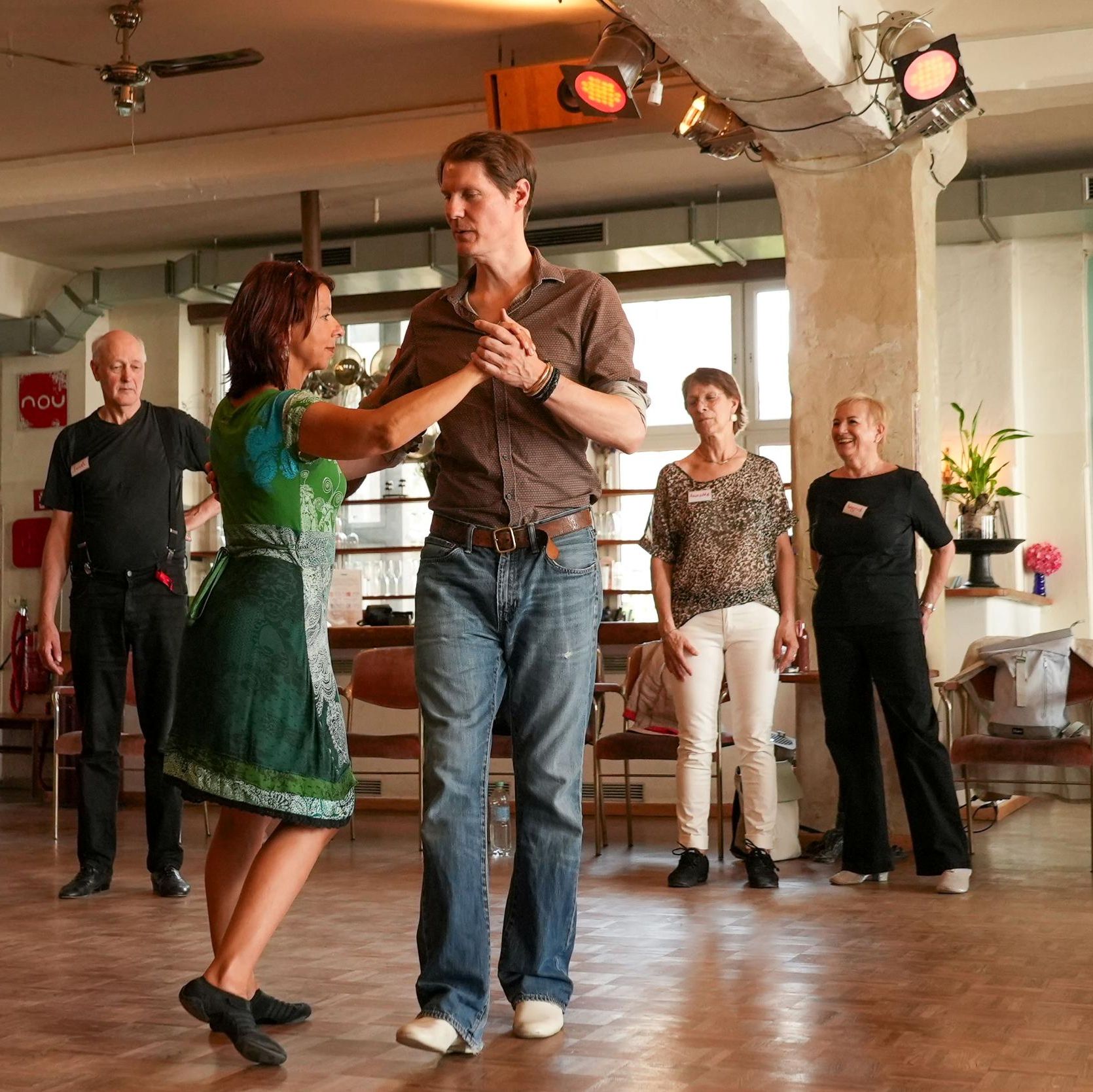 Teilnehmer üben Tango-Schritte in einer Trauer- und Tango-Veranstaltung des Malteser Hilfsdienstes, Fokus auf Tanz und Gemeinschaft.