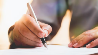 Testament verfassen: Nahaufnahme einer Hand mit Stift in der Hand