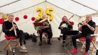 Vier Musiker spielen auf einer kleinen Bühne im Festzelt beim 35-jährigen Jubiläum des Hospiz-Zentrums, im Hintergrund hängen goldene Luftballons mit der Zahl 35.