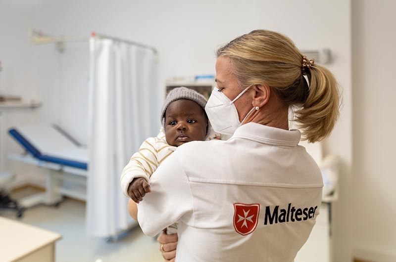 Eine Ärztin hält ein Baby auf dem Arm