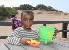 Ein Kind des Kinderheims spielt bei einem Ausflug am Strand