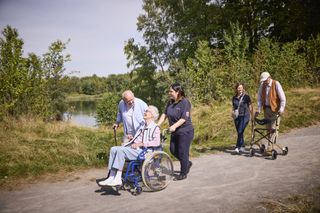 Malteser Ehrenamtliche beim spazieren im grünen mit älteren menschen