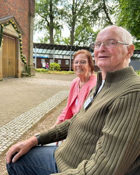 Zwei Personen sitzen auf einer Bank vor einer Kirche