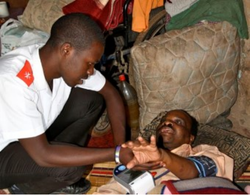Care worker visiting Xolani at home and checking his blood pressure.