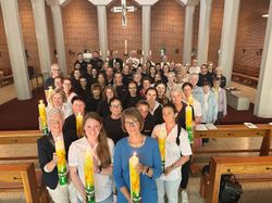 Personengruppe aus dem Pflegebereich mit großen Kerzen vor dem Kirchenaltar mit Blick in die Kamera.