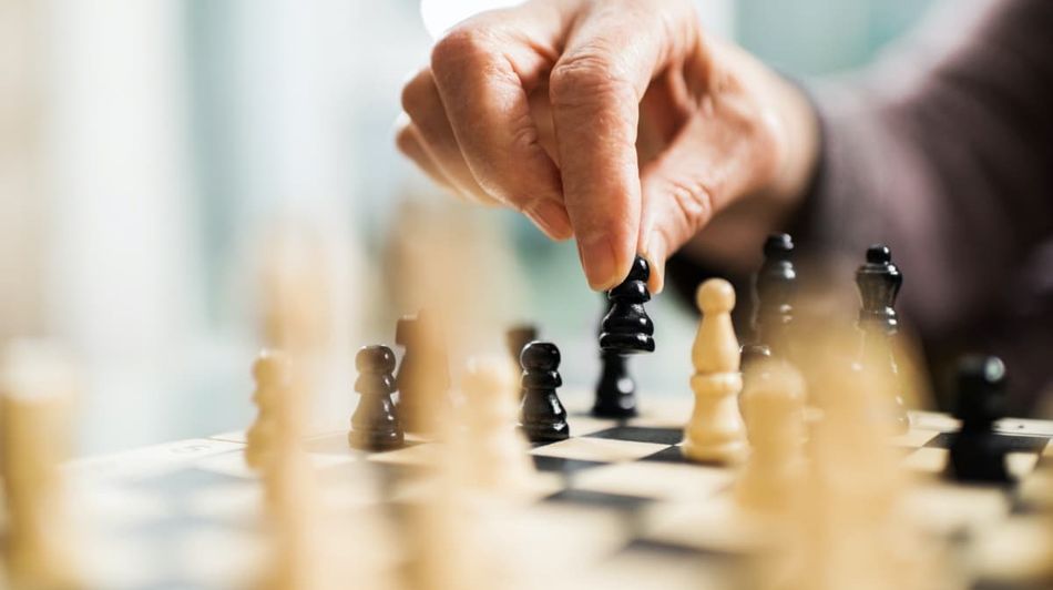 Es wird ein Senior gezeigt, welcher Schach spielt.