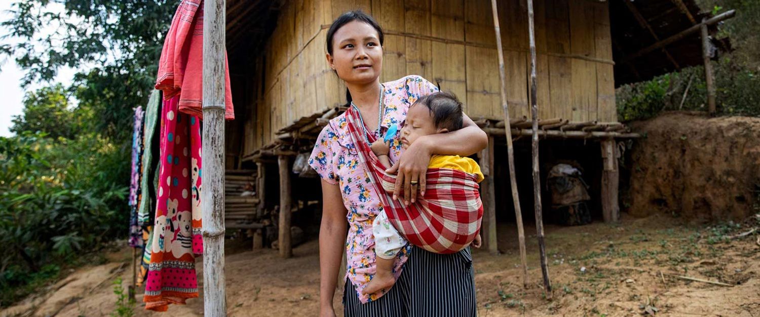 Eine thailändische Mutter trägt ihr Baby in einem Tragetuch.