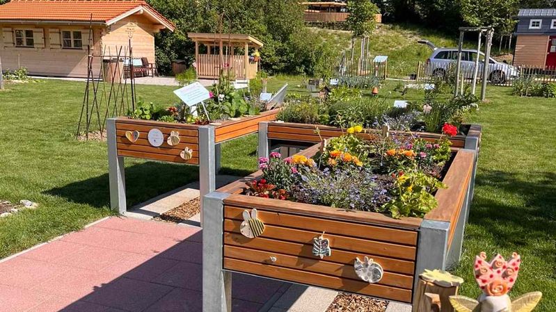 Hochbeete in einer begrünten Gartenanlage.