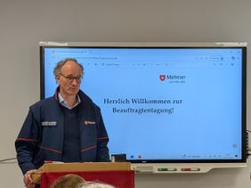 Diözesanleiter Dr. van Lengerich eröffnet die Tagung vor einem Smartboard das "Willkommen zur Beauftragtentagung" anzeigt