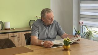 Ein Senior mit einem Hausnotruf-Armband beim Zeitunglesen