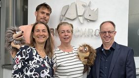Vier Personen stehen mit zwei Igel Handpuppen vor dem Eingang der Firma Betz Chrom und lächeln in die Kamera.