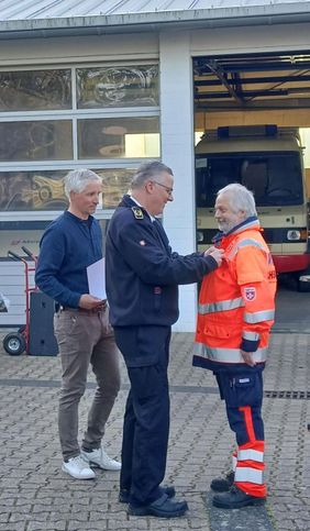 Kreisbrandmeister Thomas Weiler und Peter Fenkl, Vorsitzender Kreisfeuerwehrverband überreichen die Ehrennadel an Hans Günter Hornfeck.