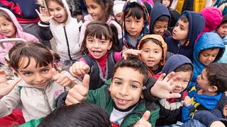 Viele Kinder winken fröhlich in die Kamera