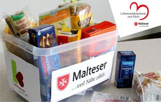 Transparente Kunststoffbox, gefüllt mit Lebensmitteln, darauf ein Aufkleber „Malteser ...weil Nähe zählt“, daneben ein Päckchen Kaffee