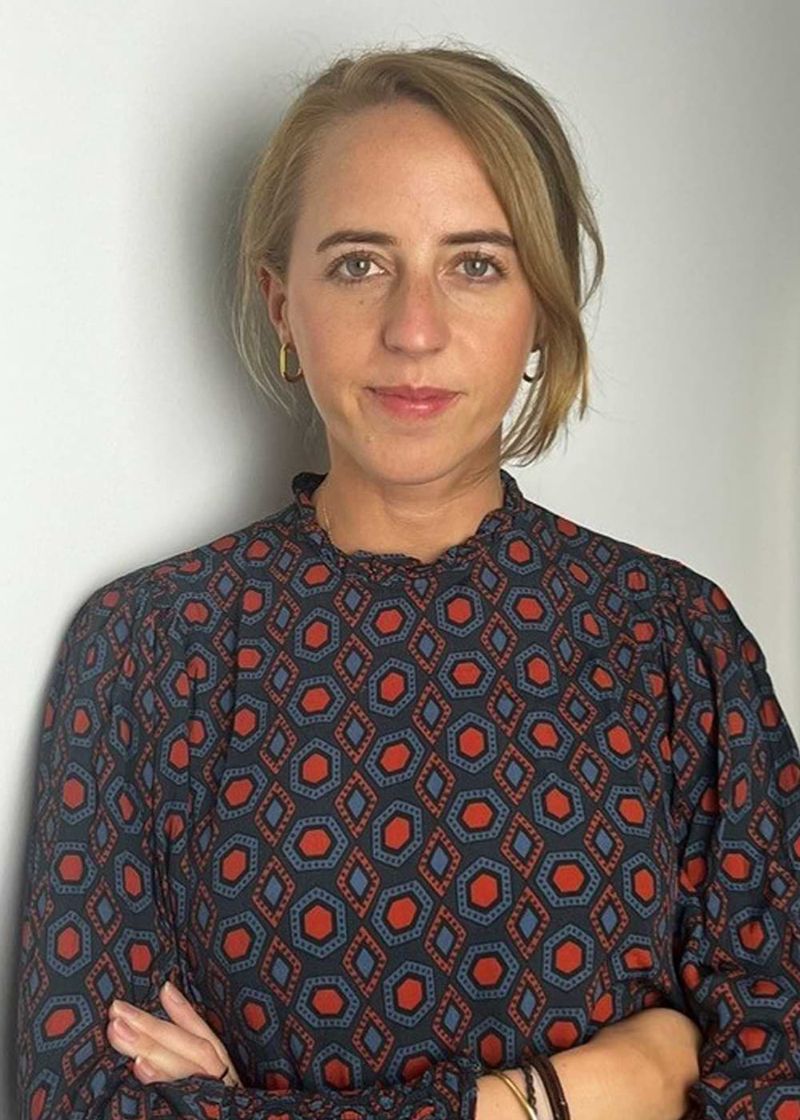 Eine dezent lächelnde junge Frau mit verschränkten Armen.