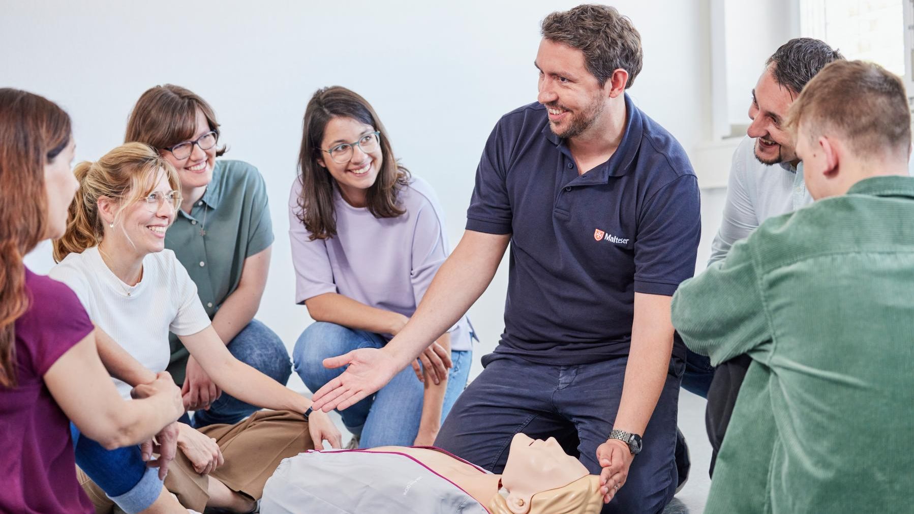 Erste-Hilfe-Ausbilder der Malteser steht vor einer Gruppe in einem Erste-Hilfe-Kurs