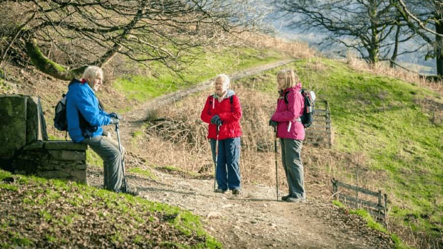 Drei Senioren machen eine Pause während des Wanderns. 