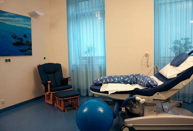 Kreisssaal mit Untersuchungsstuhl, Sessel und blauem Gymnastikball.
