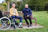 Zwei Männer unterhalten sich, einer hat einen Rollstuhl dabei