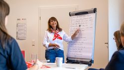 Eine Frau steht an einem Flipchart und erklärt etwas.